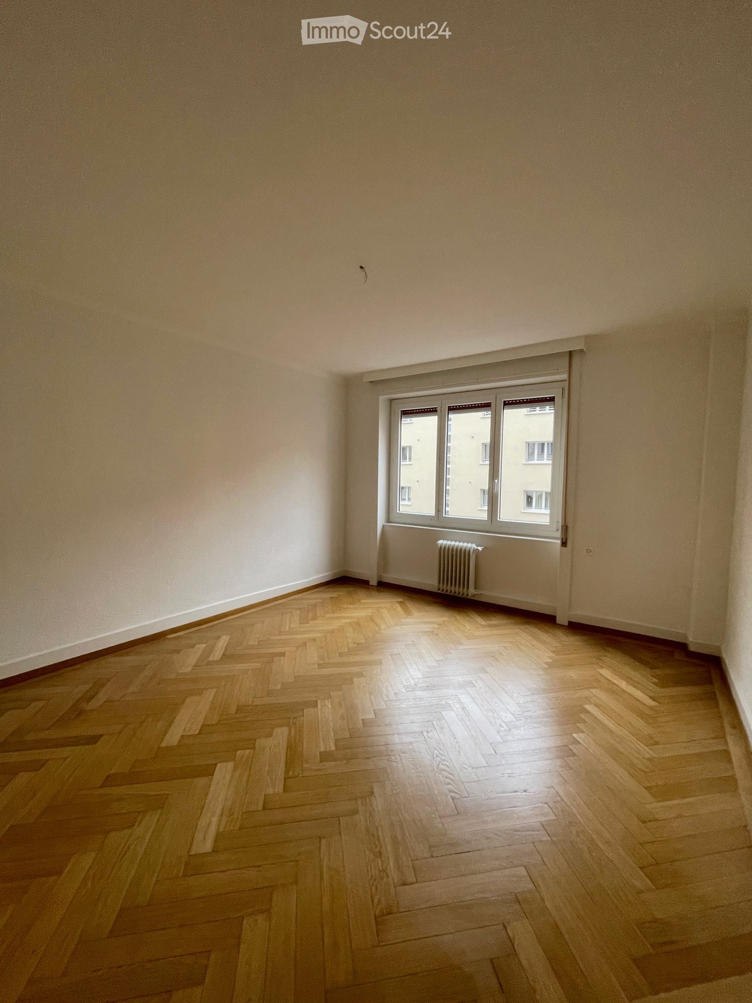 wooden parquet floor, large windows, radiator, white walls