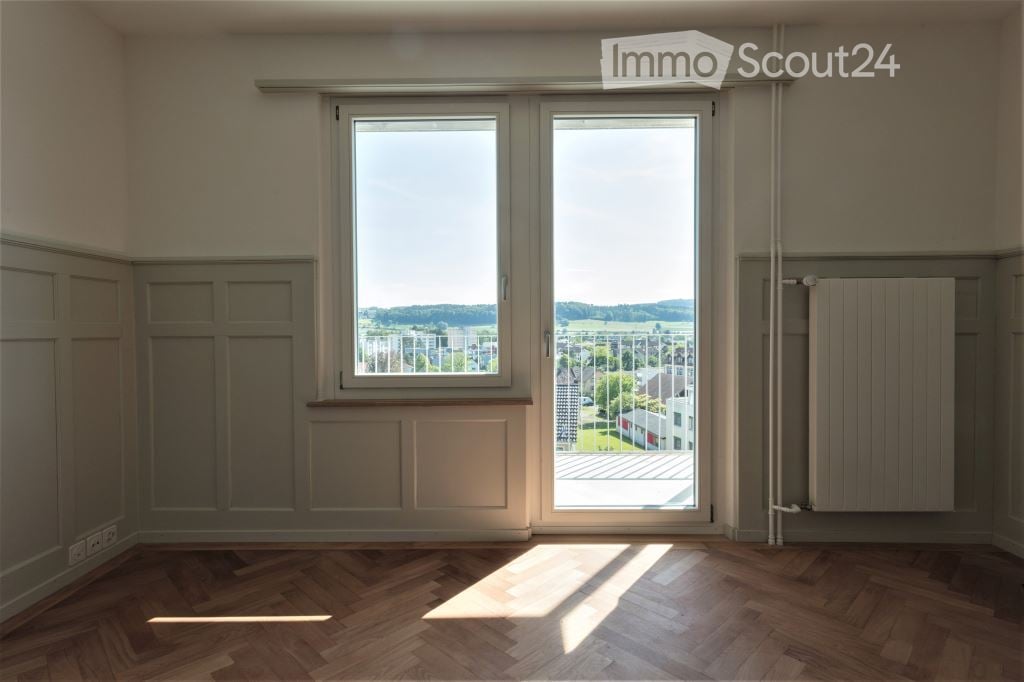 Empty room with sliding doors leading to balcony, wooden floor, and white walls