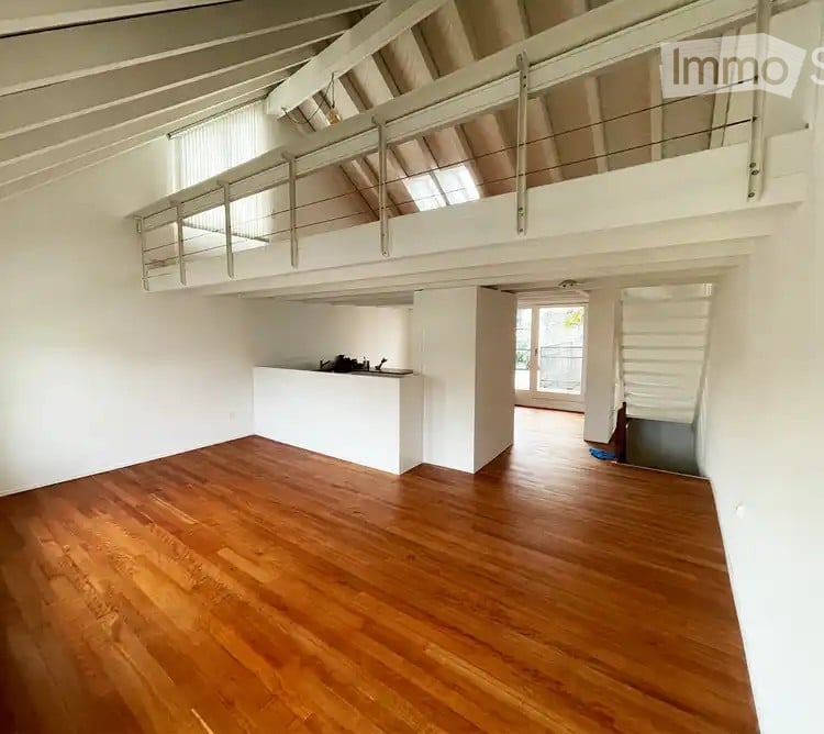 empty room, wooden floor, white walls, mezzanine with balcony, windows on ceiling, open kitchen area