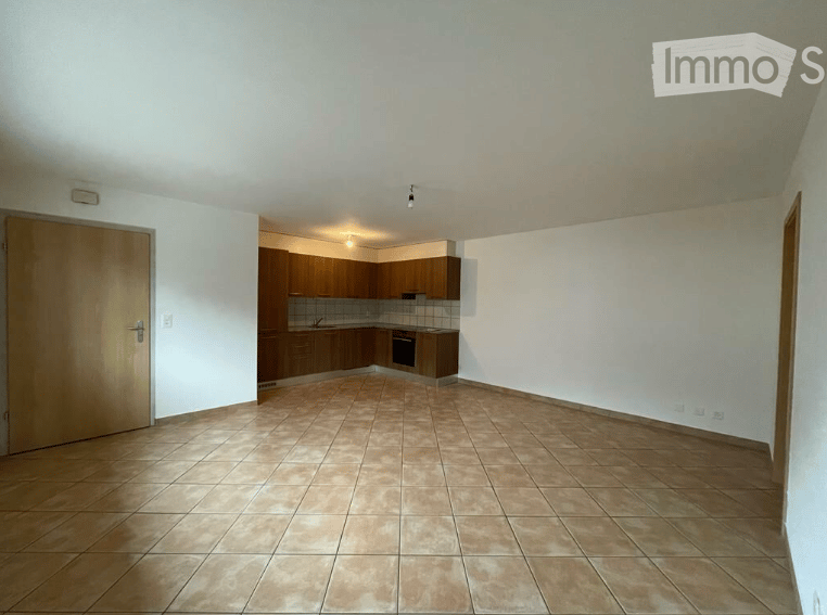 Open room with empty kitchen area, tiled floor, wooden cupboards