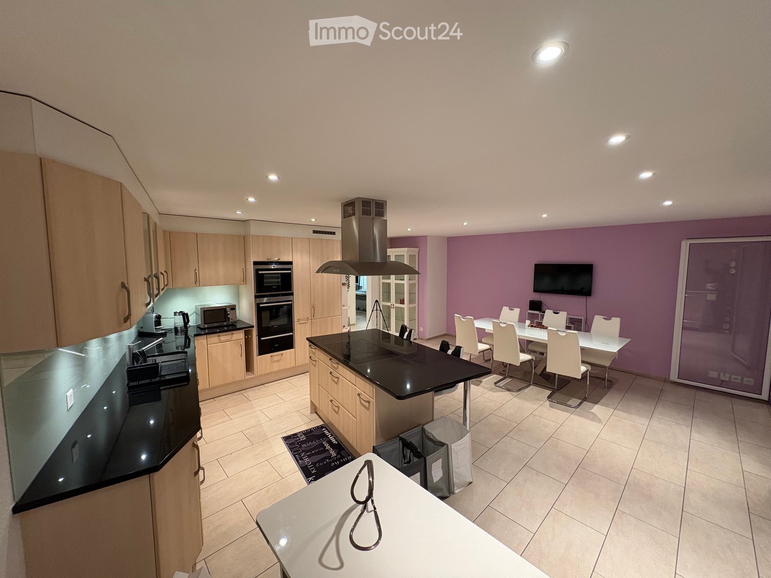 open kitchen, island, dining table, chairs, TV, microwave, oven, sink, cabinets, black countertops