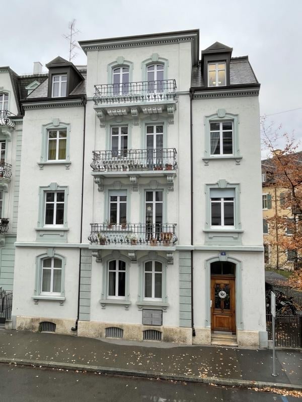 5 story white painted building, multiple balconies, wooden front door