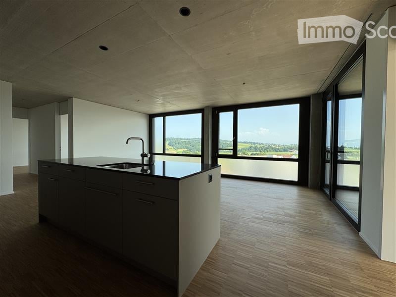 an open space with kitchen area, kitchen island, large windows and balcony