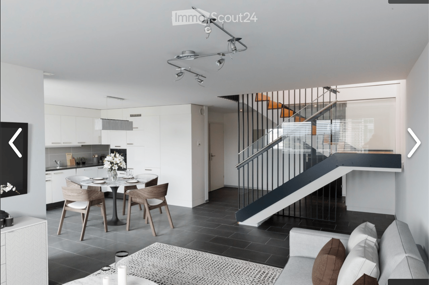 modern style, gray carpet, white kitchen with black countertop, table and chairs, modern lamps, staircase