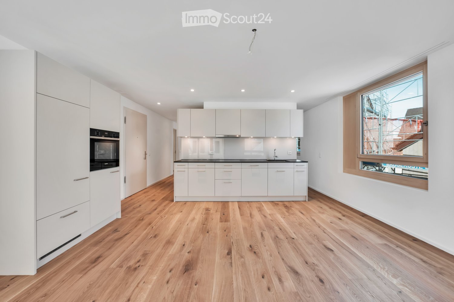 modern kitchen with wooden floor, white cabinets, black appliances, large window