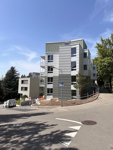 modern multi-story building, large windows, balconies, grey and white facade