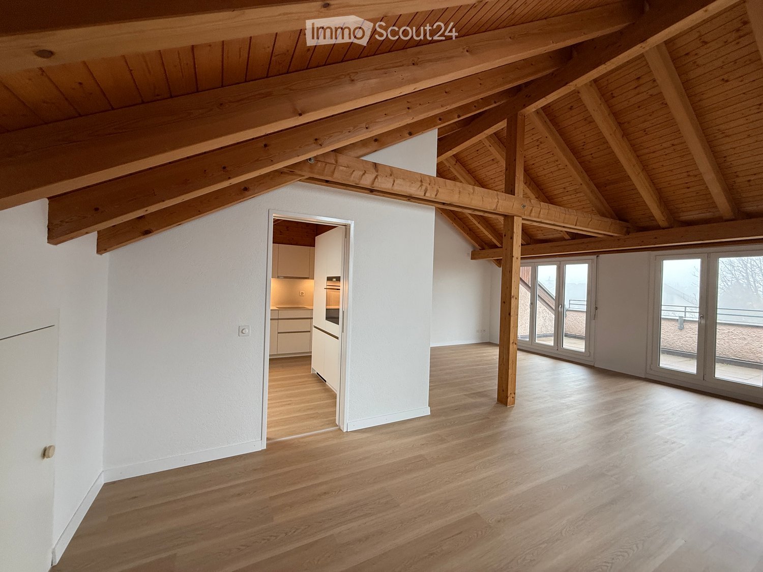 wooden beams, wooden floor, white walls, glass doors, kitchen area, empty room