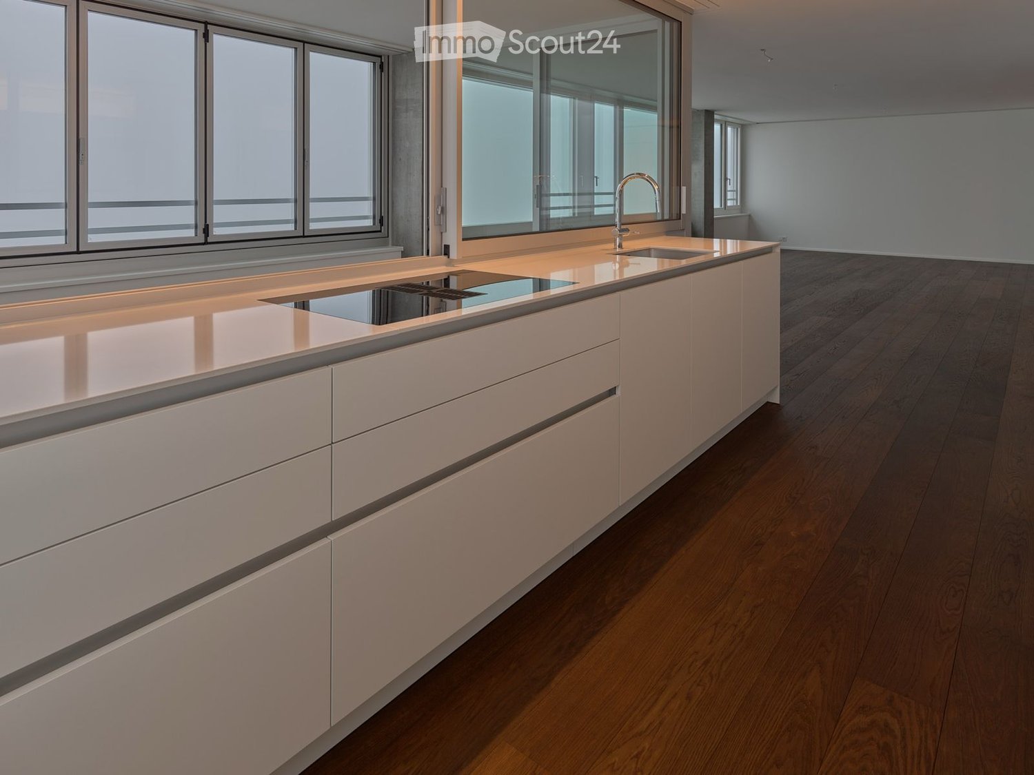 modern kitchen with white cabinets, stainless steel stovetop, wooden floor, and windows