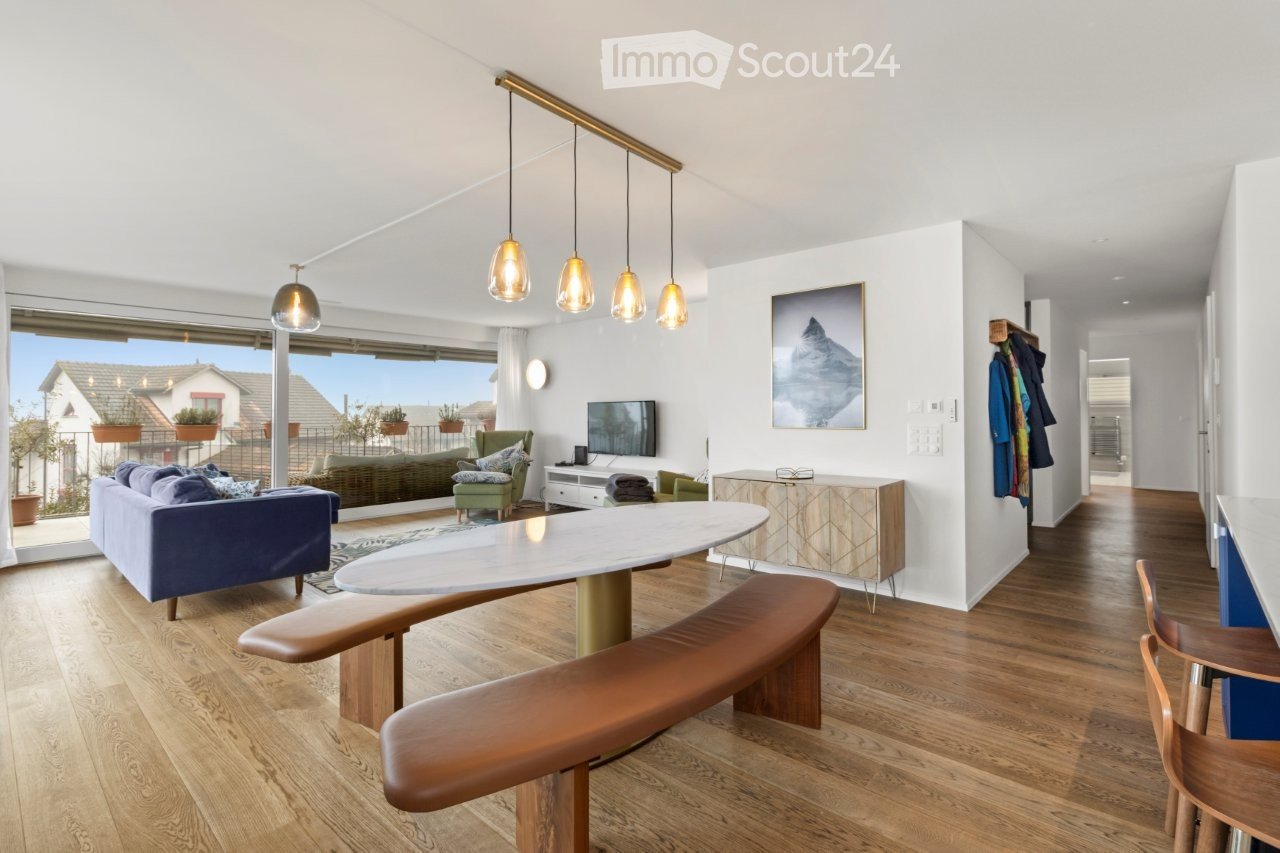 modern living room with wooden floor, large table, blue sofa, and large glass doors leading to balcony