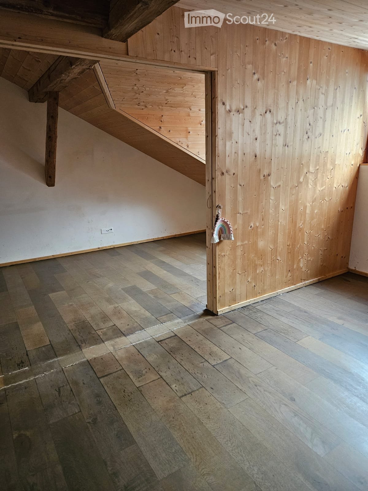 empty room, wooden flooring, exposed wooden beams, wooden walls, small power outlet