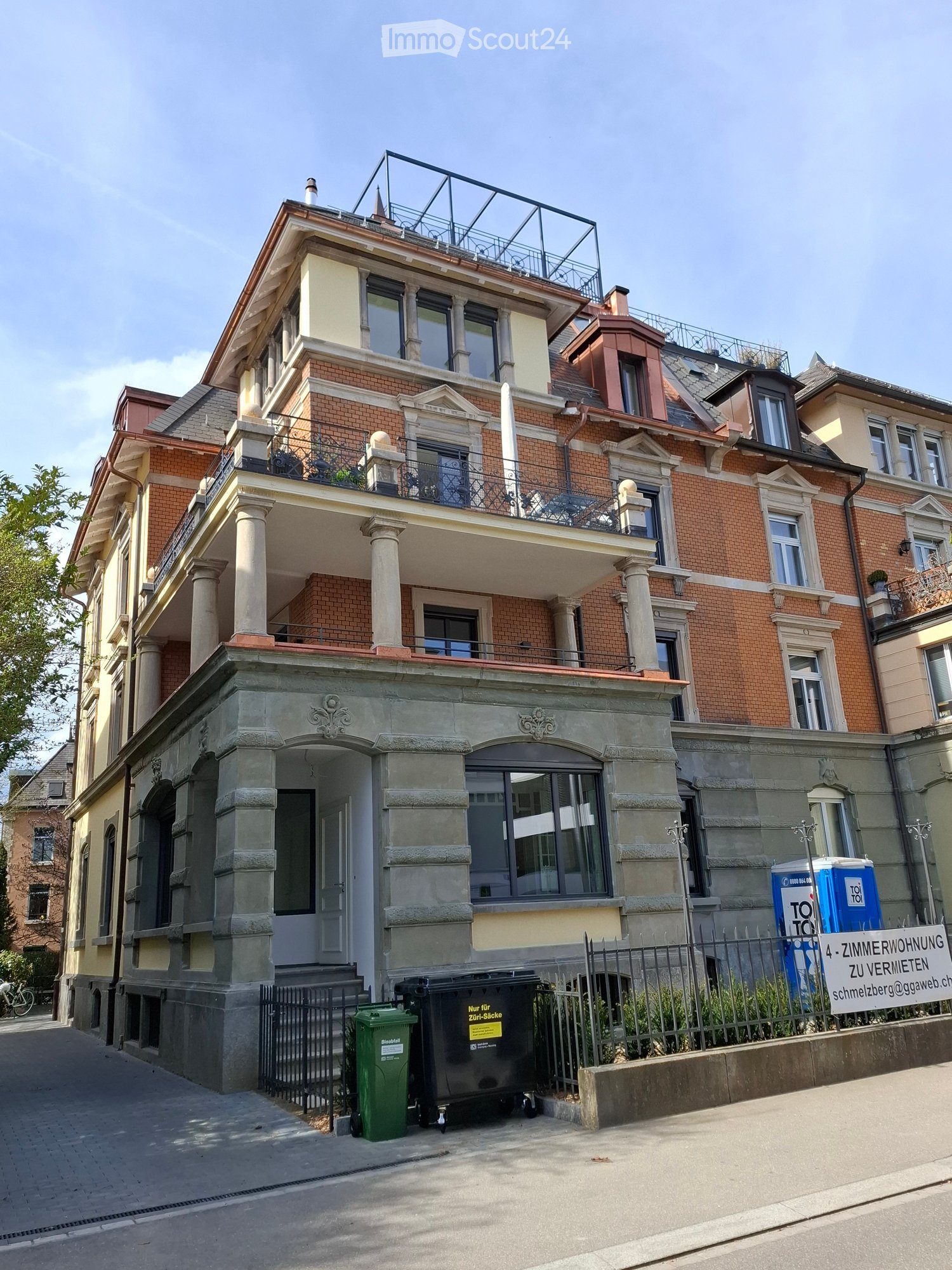 3 story building, brick facade, multiple balconies, large windows, entrance with stairs