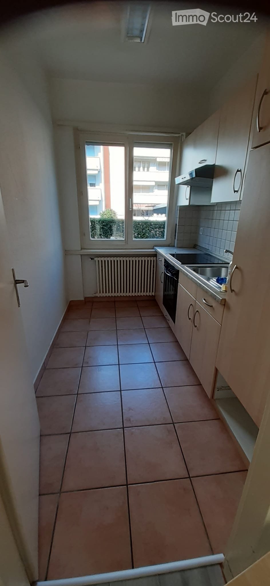 empty kitchen with tiled floor, white walls, window, cabinets, sink, stove, and a radiator