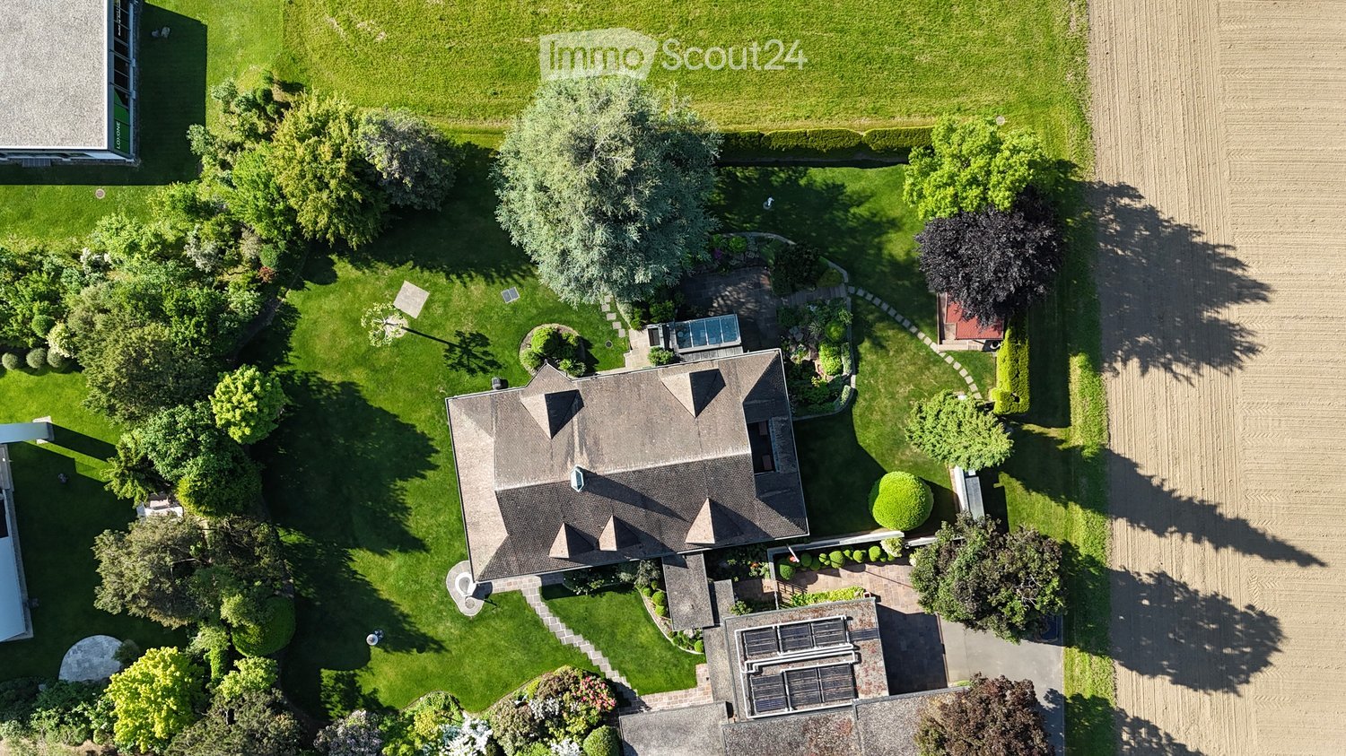 House with a swimming pool, solar panels, garden, and trees
