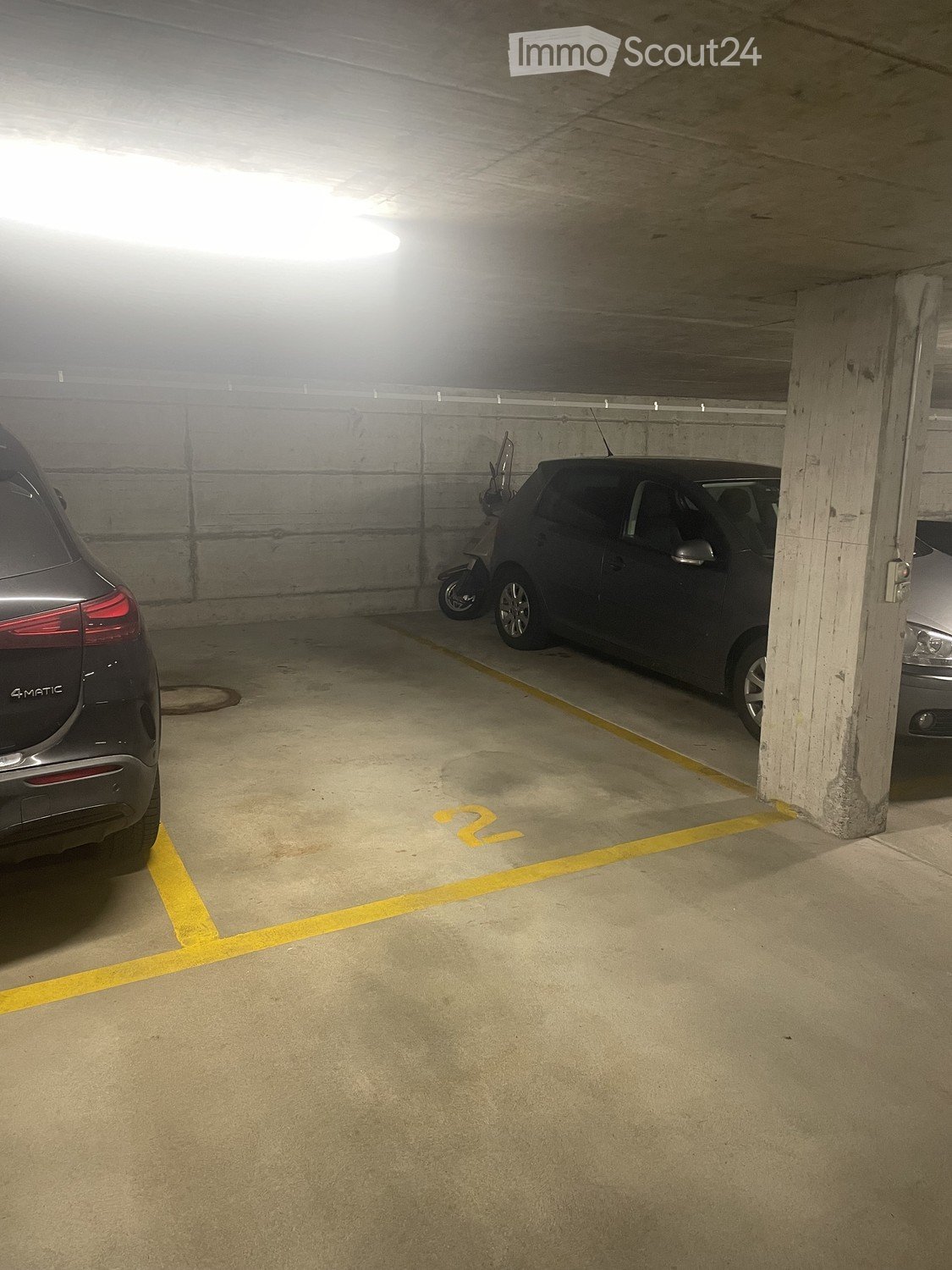 {"visible_features": [], "type": "Garage", "objects": ["car", "motorcycle"], "description": "An underground parking space with two cars parked, one of which is a motorcycle. The space has yellow markings on the floor.", "localized_descriptions": {"EN": "A