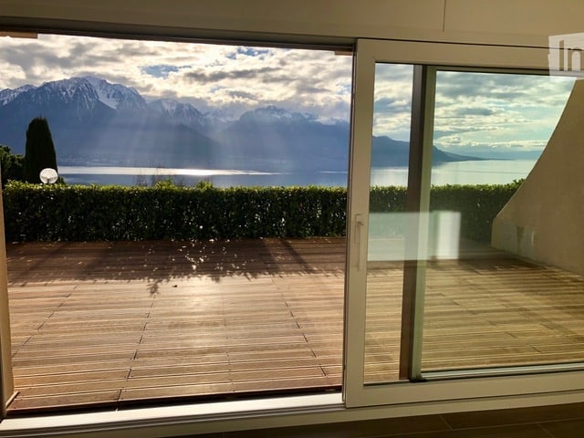 sliding glass door, wooden deck, hedges, lake, mountains