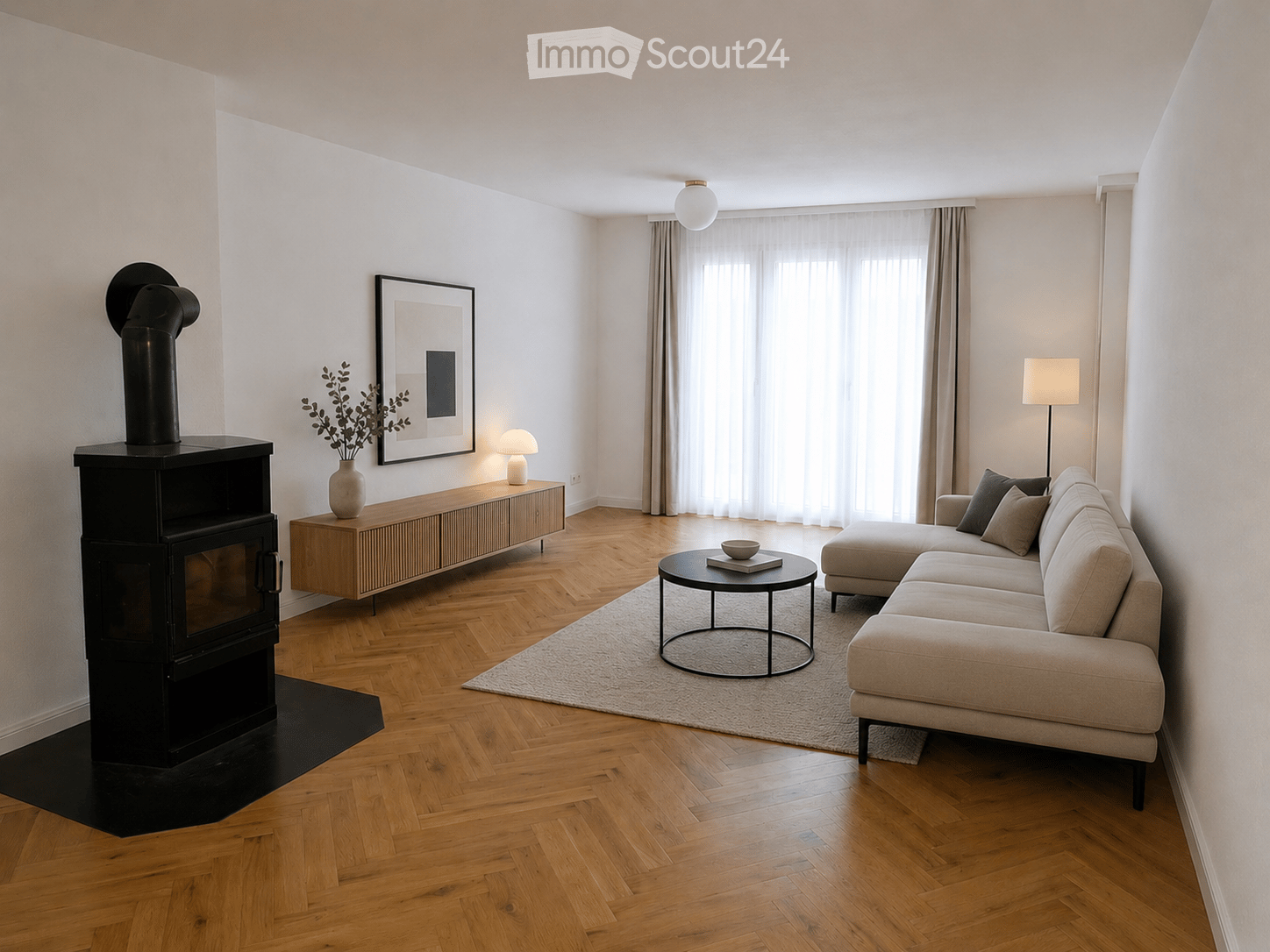 Modern living room with herringbone wooden flooring, a fireplace, a sectional sofa, a coffee table, side table, and decorative items.