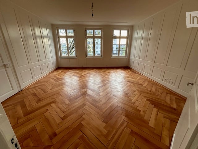 empty room, wooden parquet floor, white walls, three windows, wooden doors