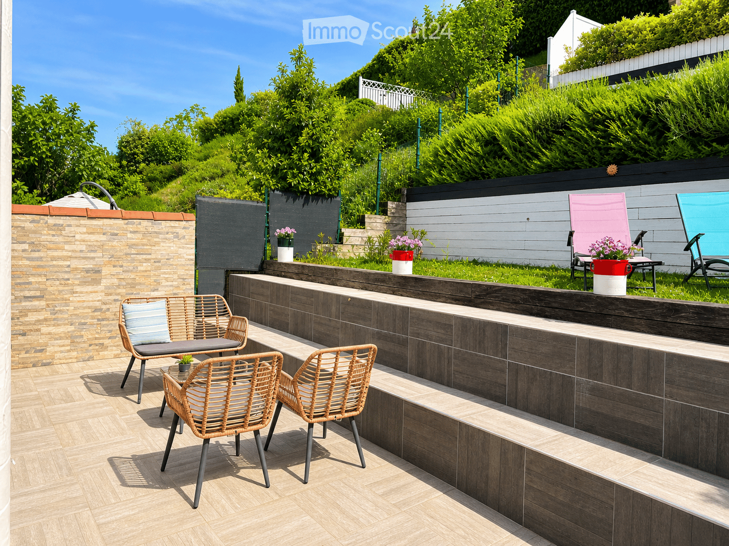 Garden / Outdoor Area. Outdoor seating area with wicker chairs, a table, and planters with flowers.