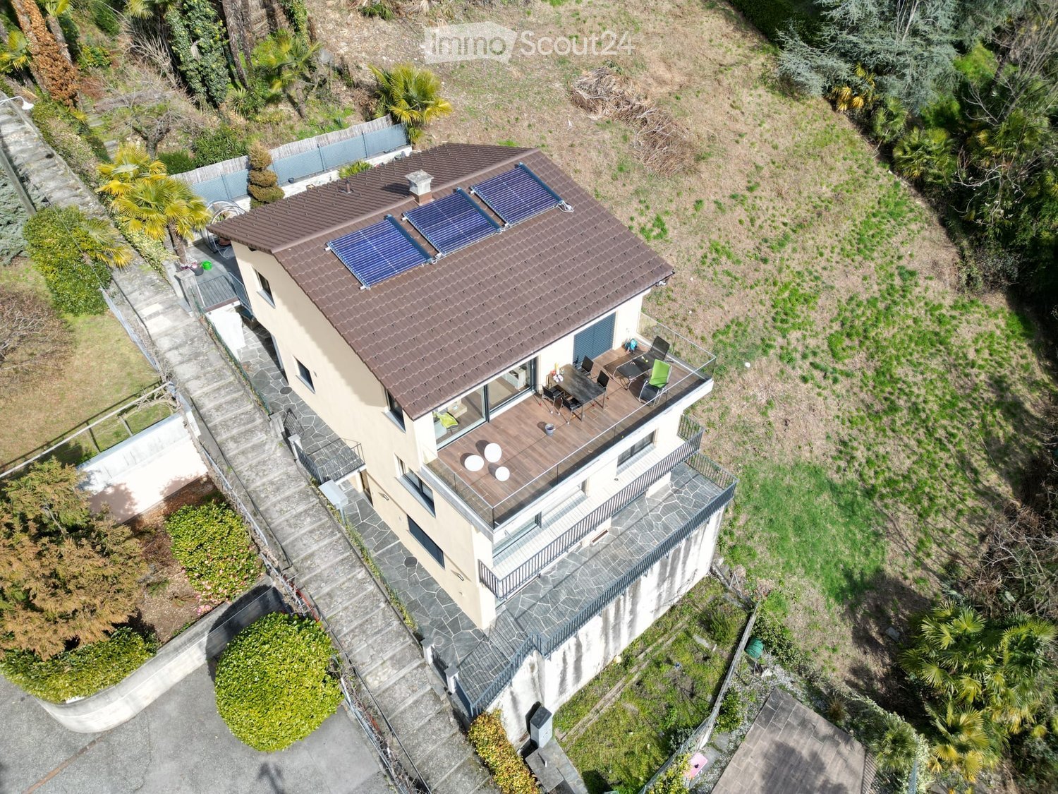 modern house, brown roof, solar panels, terrace with furniture, surrounded by greenery