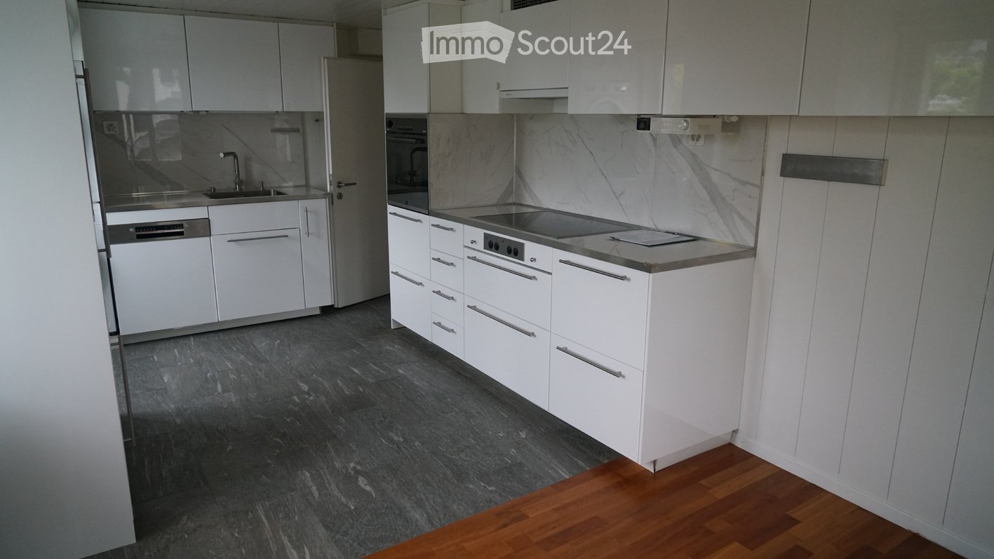 Modern kitchen with white cabinets, stainless steel appliances, marble backsplash, and dark grey tiled floor.