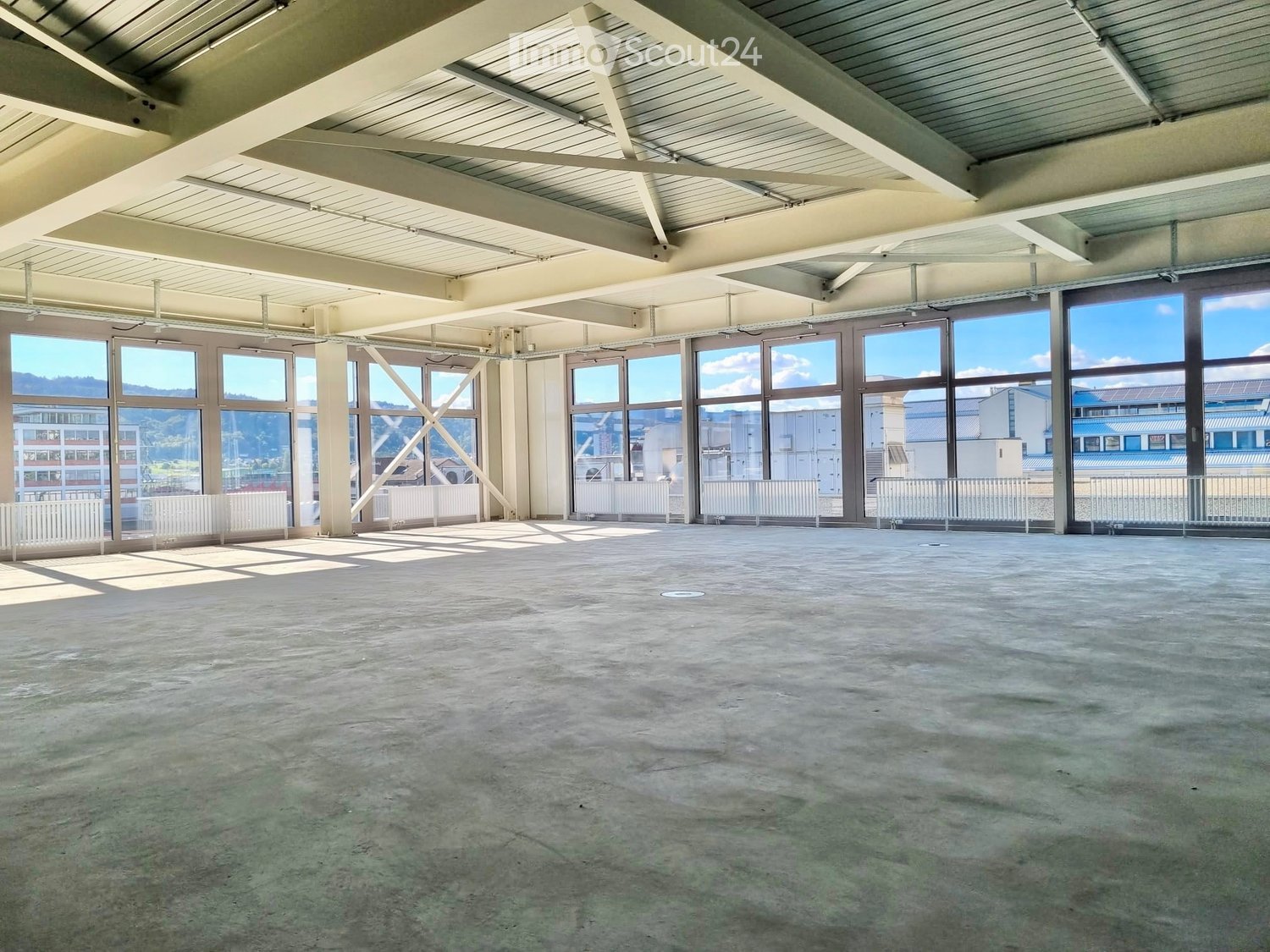 Unfurnished Room. Empty room with concrete floor, large windows, white railings, and exposed ceiling beams.