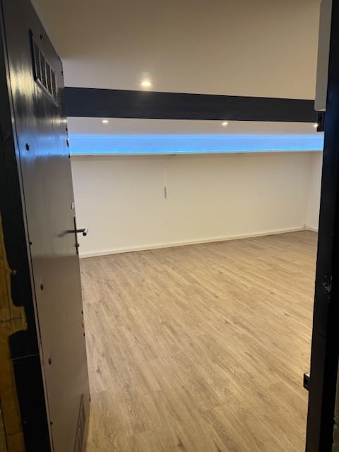 Unfurnished Room. Empty room with light wooden flooring, white walls, and a modern black and white accent wall. No furniture or equipment present.