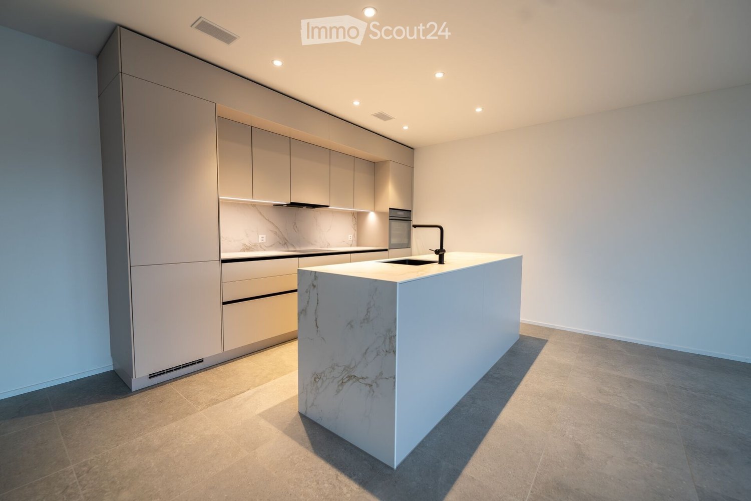 Modern kitchen with light grey cabinets, marble countertop, and built-in appliances.
