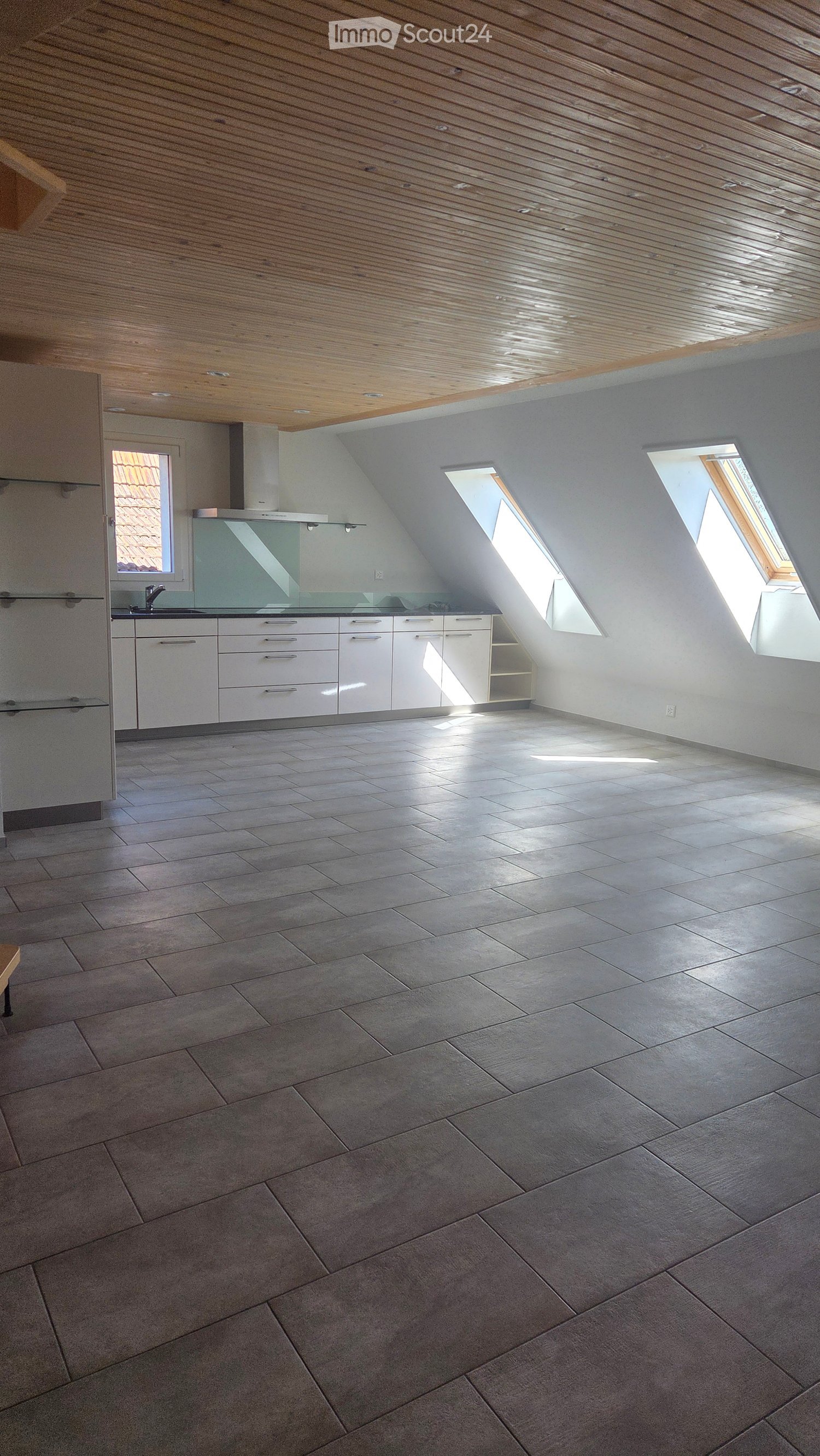 Empty kitchen with white cabinets, stainless steel sink, and tiled floor. Skylight windows allow natural light to fill the space.