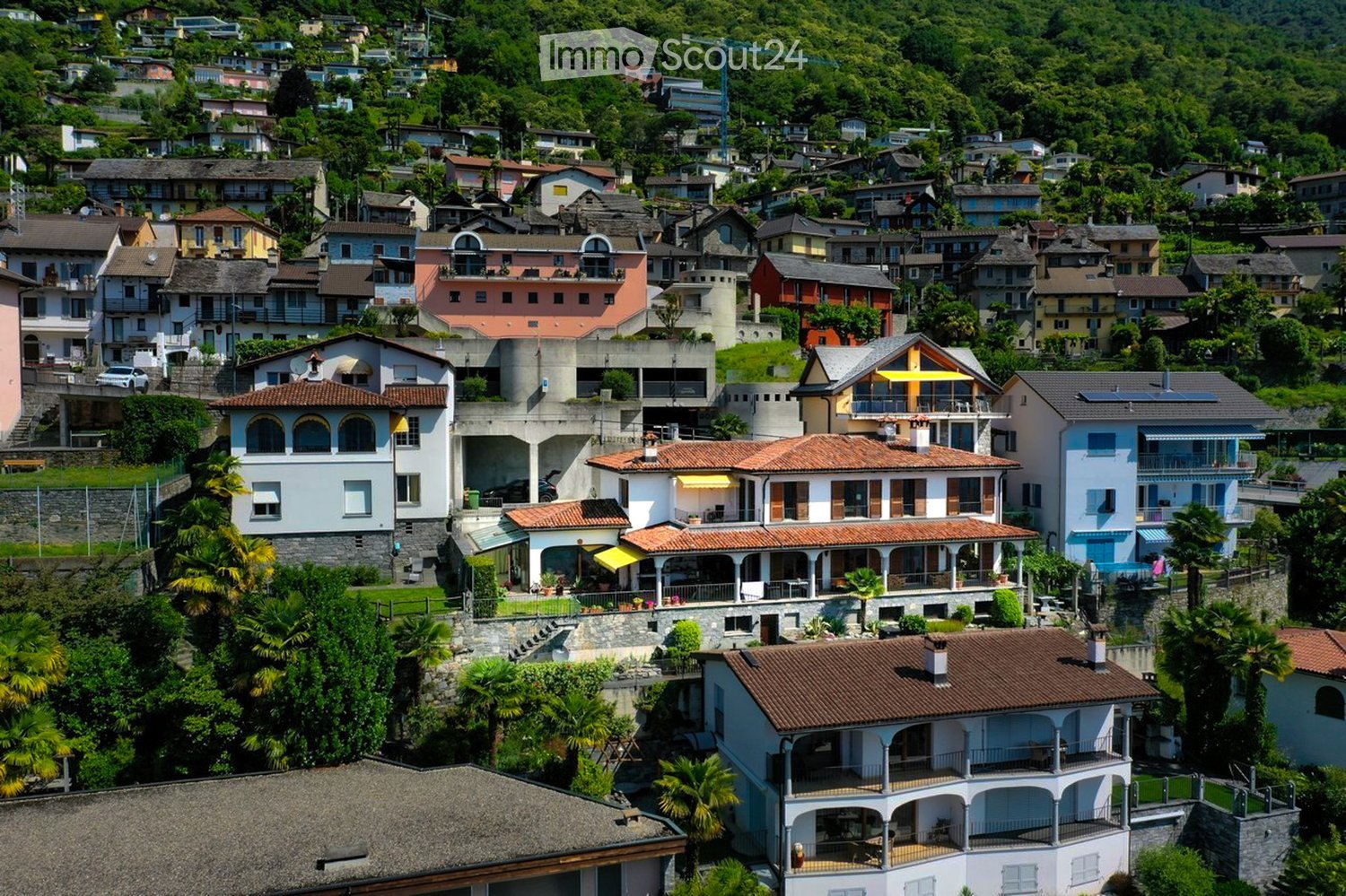 cluster of villas on a hillside, balconies, terraces, surrounding greenery, views of mountains