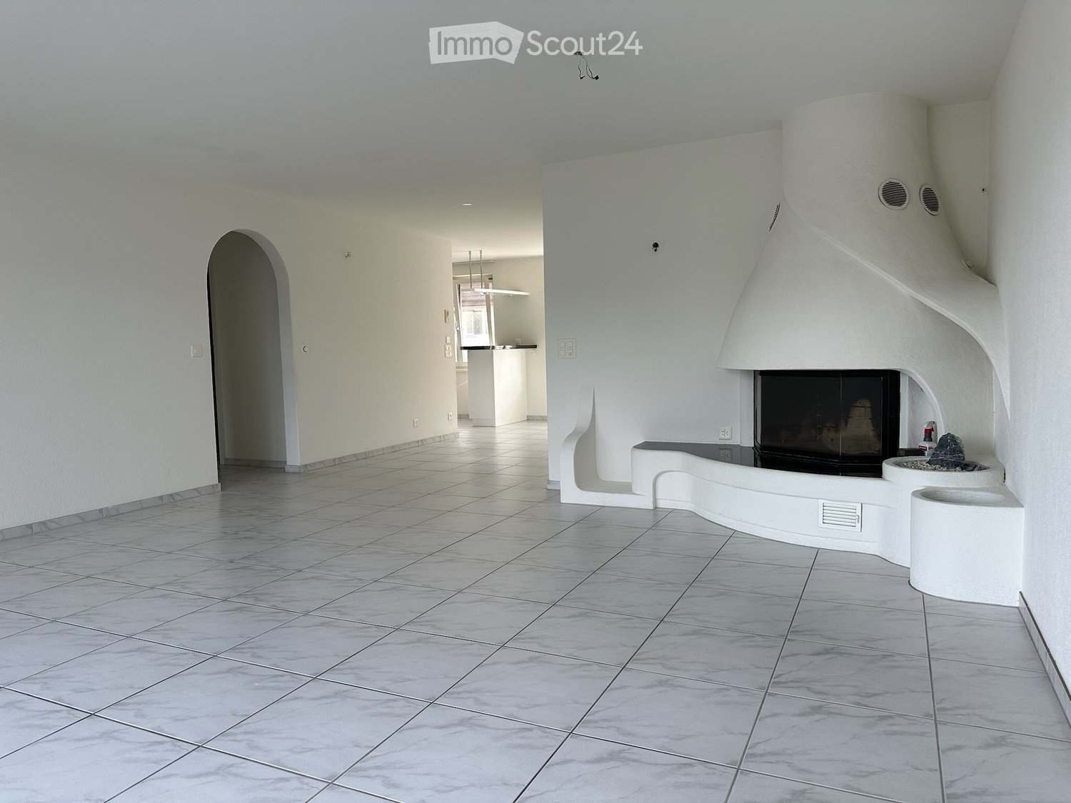 Bright, modern hallway with white walls, tiled floor, and a built-in fireplace with a decorative stone centerpiece.