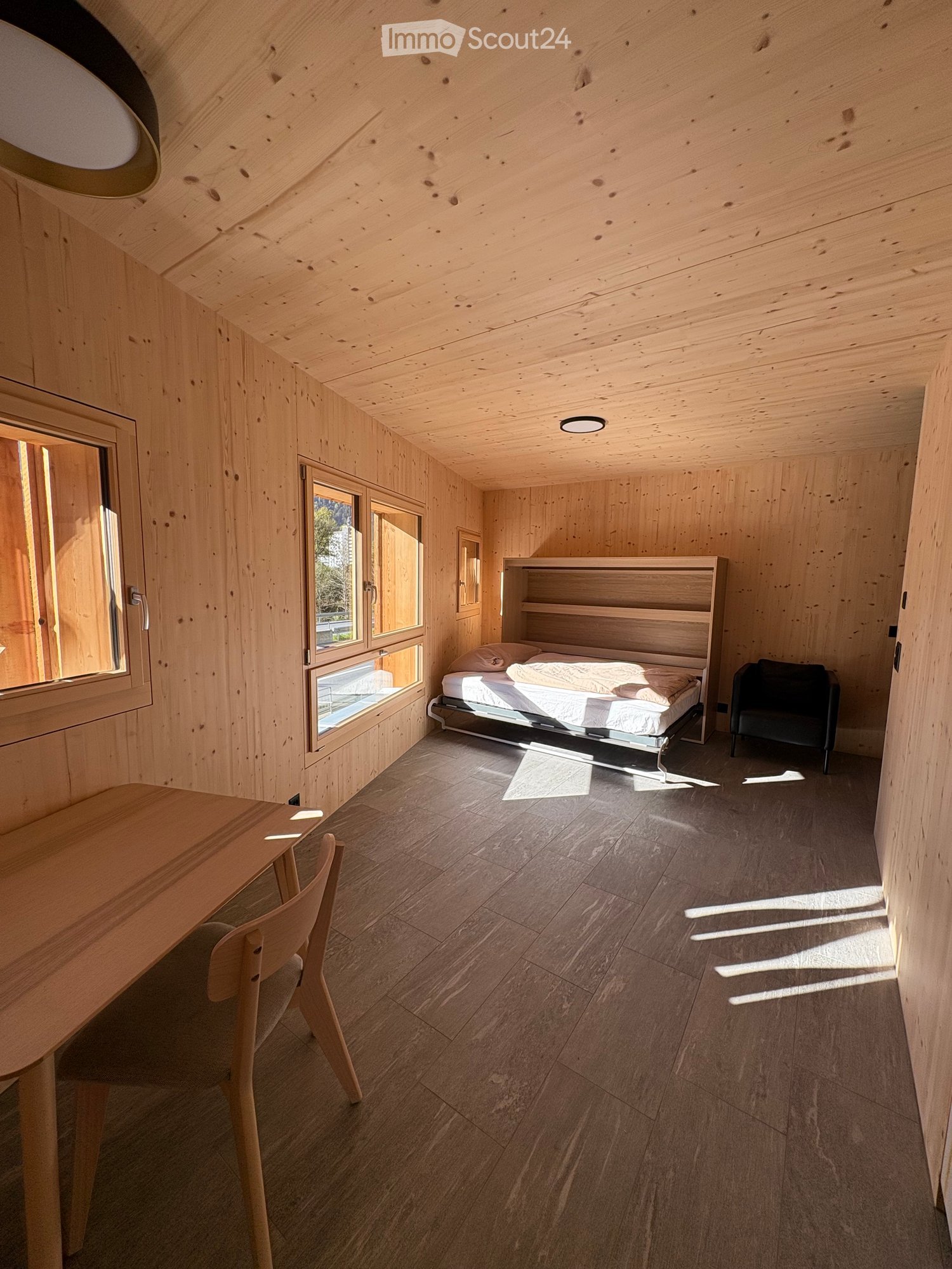room with wooden walls, wooden floor, bed, chair, desk