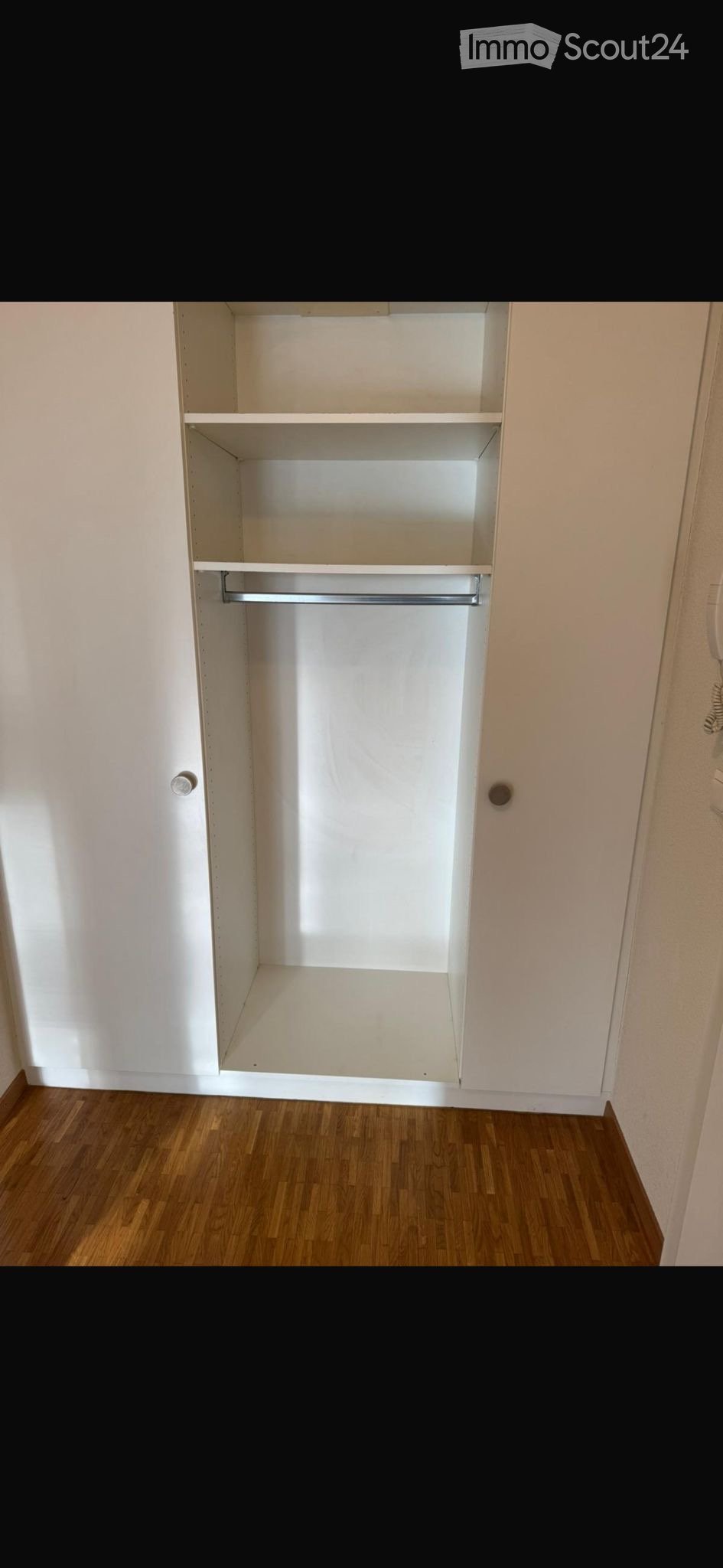 Empty room with wooden flooring and a built-in closet with shelves and a hanging rod.