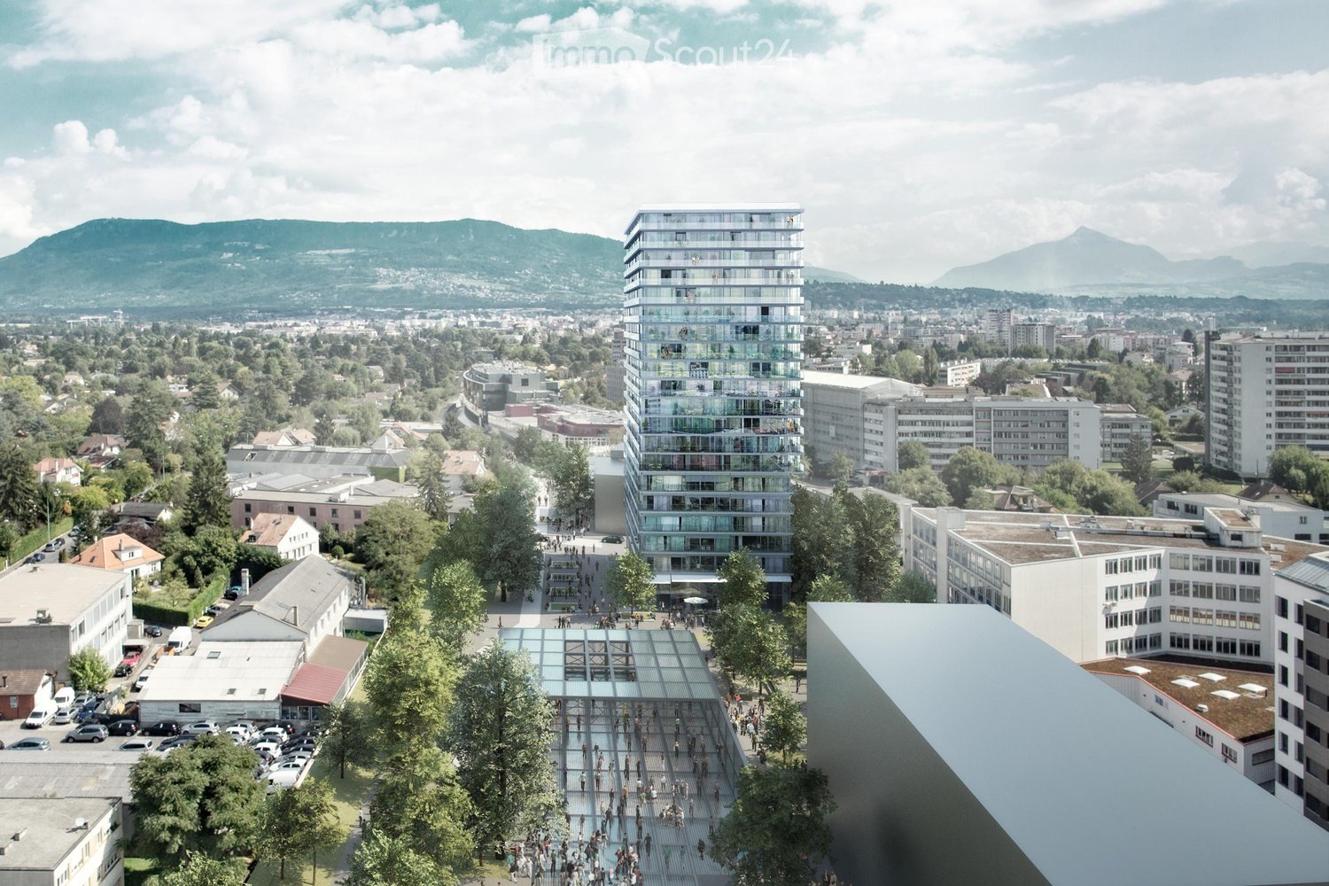 A modern urban campus with a tall glass building, surrounded by smaller structures, trees, and a parking lot. The scene includes a glass-covered walkway and a crowd of people, with mountains in the background.