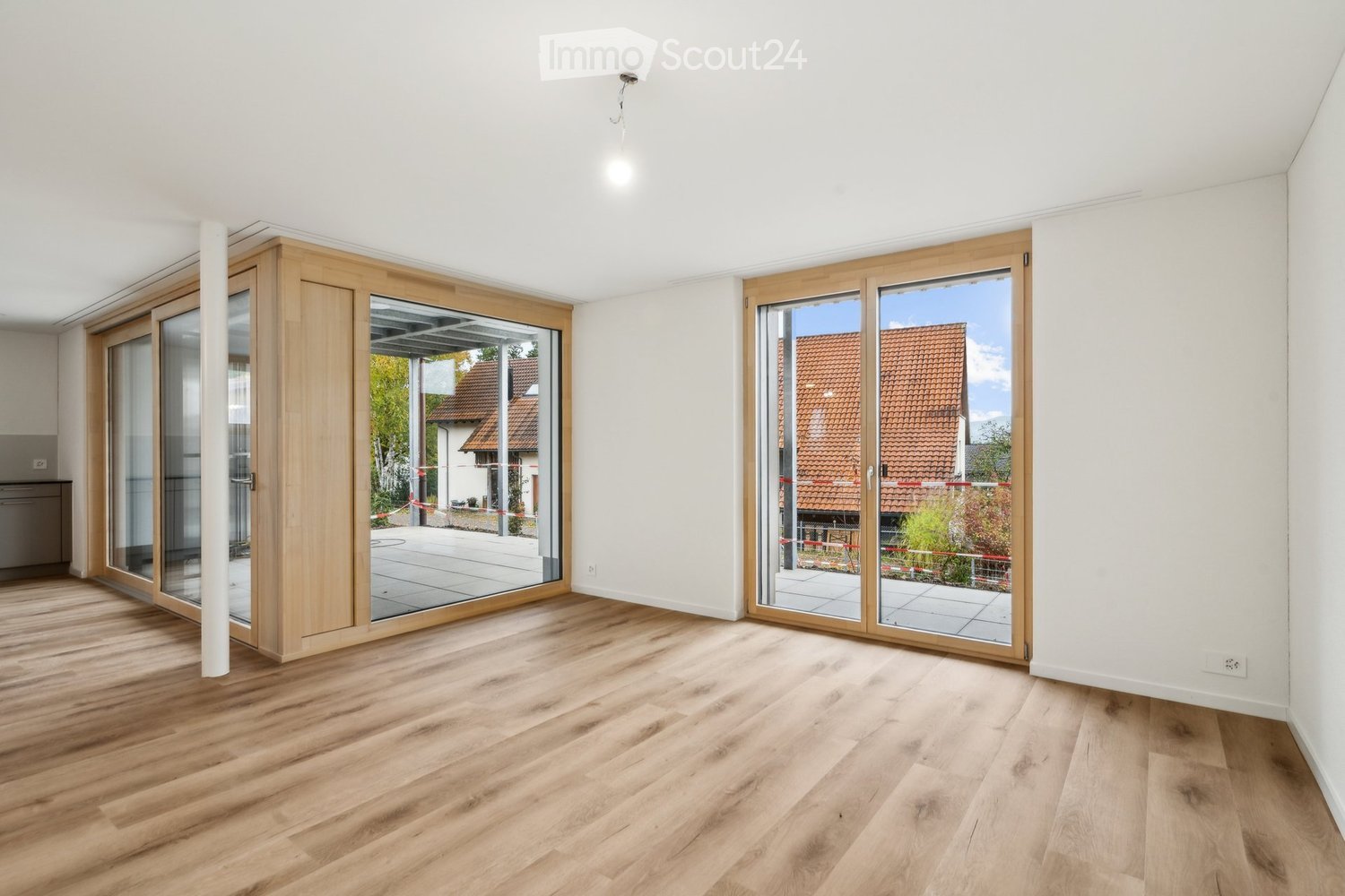 Empty room with wooden flooring, white walls, and large sliding glass doors leading to an outdoor area.