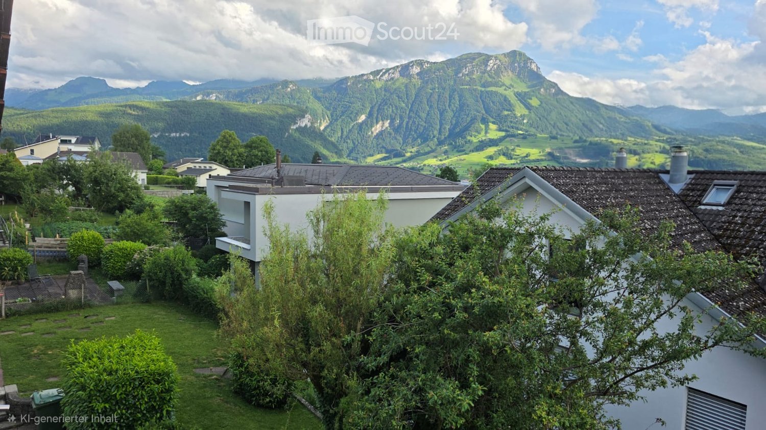 A serene garden view with a well-maintained lawn, various shrubs, and trees, overlooking a picturesque village with traditional houses and a stunning mountain backdrop.