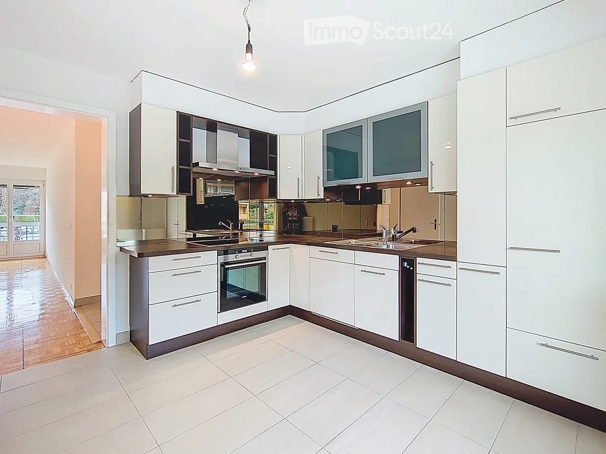 Modern kitchen with white cabinets, stainless steel appliances, and a central island with a sink and oven.