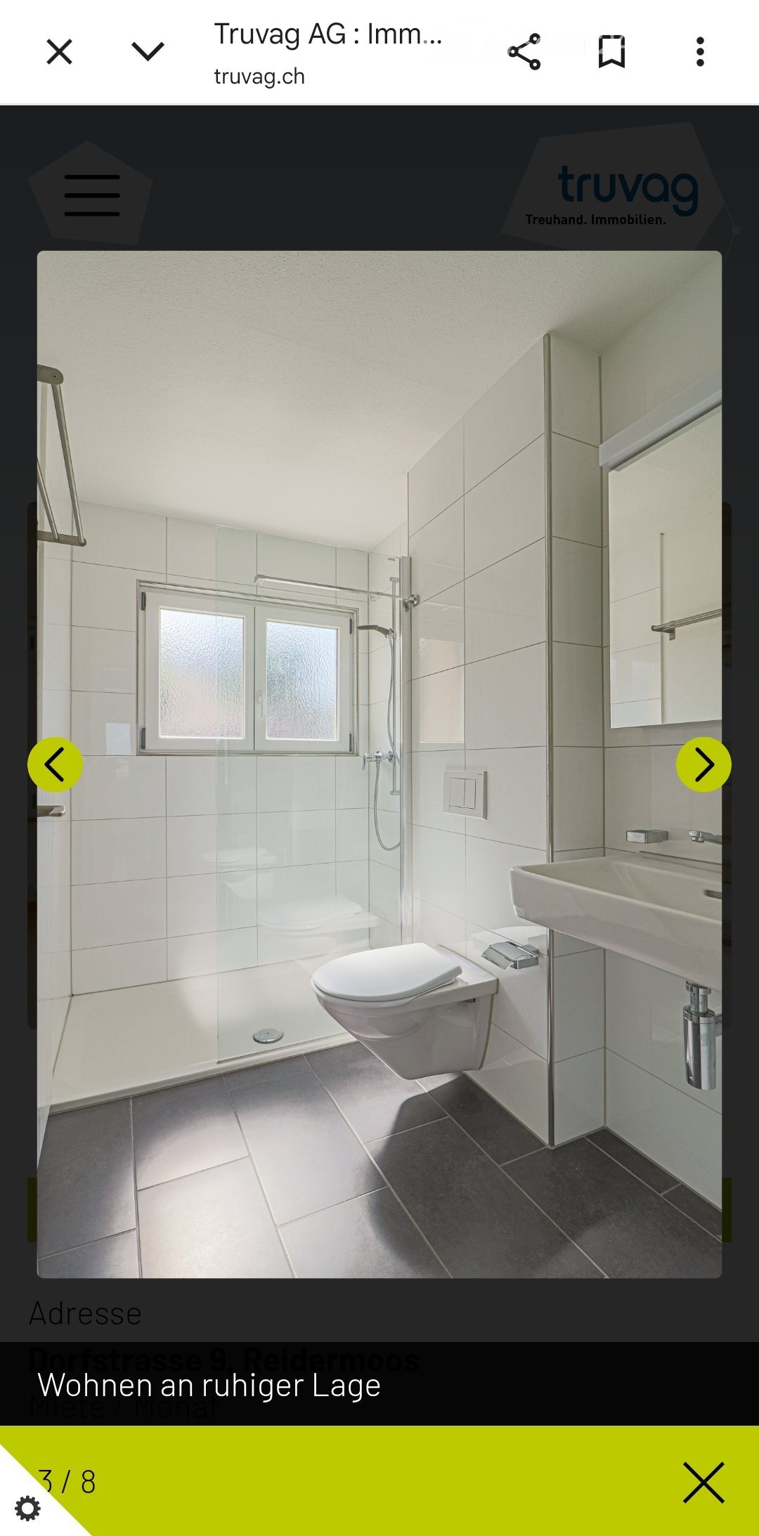 Modern bathroom with white tiles, a toilet, a sink, a glass-enclosed shower, and a mirror.