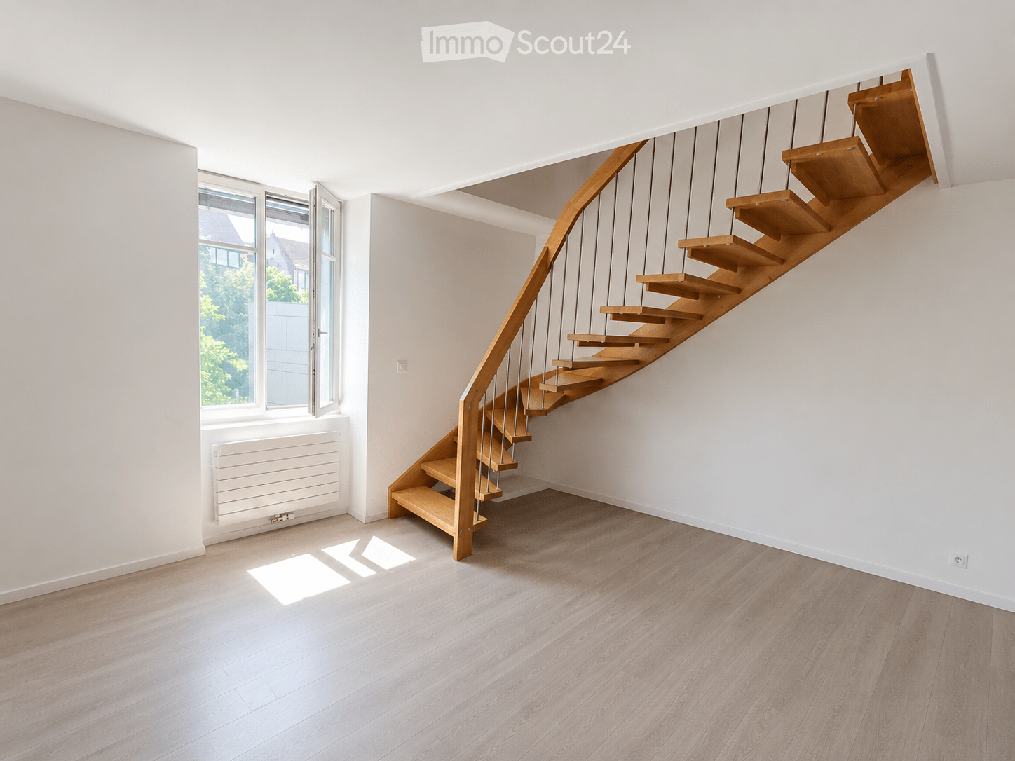 Modern hallway with wooden staircase, light-colored wooden flooring, white walls, and large windows allowing natural light.