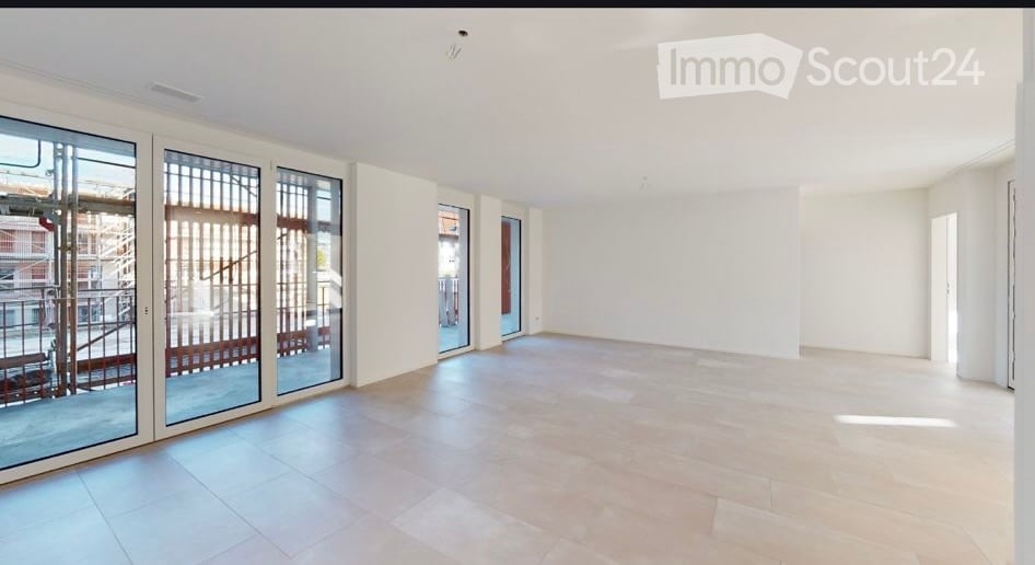 Empty room with large glass sliding doors leading to a balcony, white walls, and tiled floor.