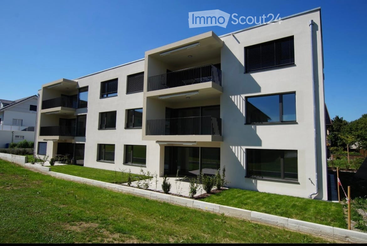Modern, three-story apartment building with white facade, large windows, and multiple balconies.