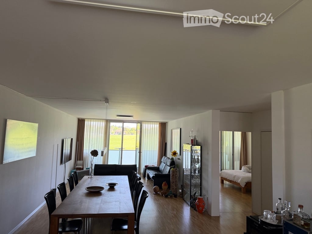 Open-plan living and dining area with modern furniture, large windows, and a view of the outdoor space.