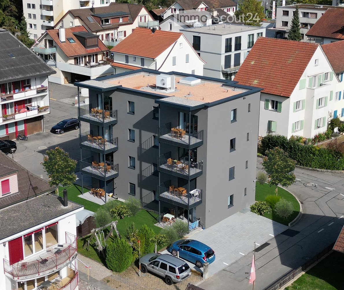 4-story apartment building, balconies on multiple floors, green lawn, multiple parked cars