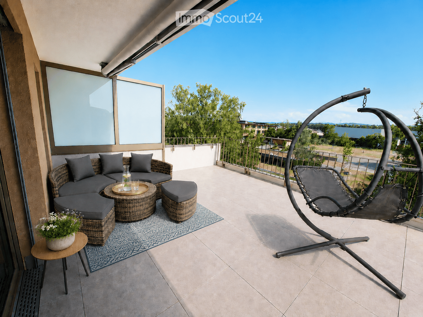 Balcony with a modern wicker sofa set, a round wicker table, a hanging egg chair, and a small wooden side table with a flower pot.