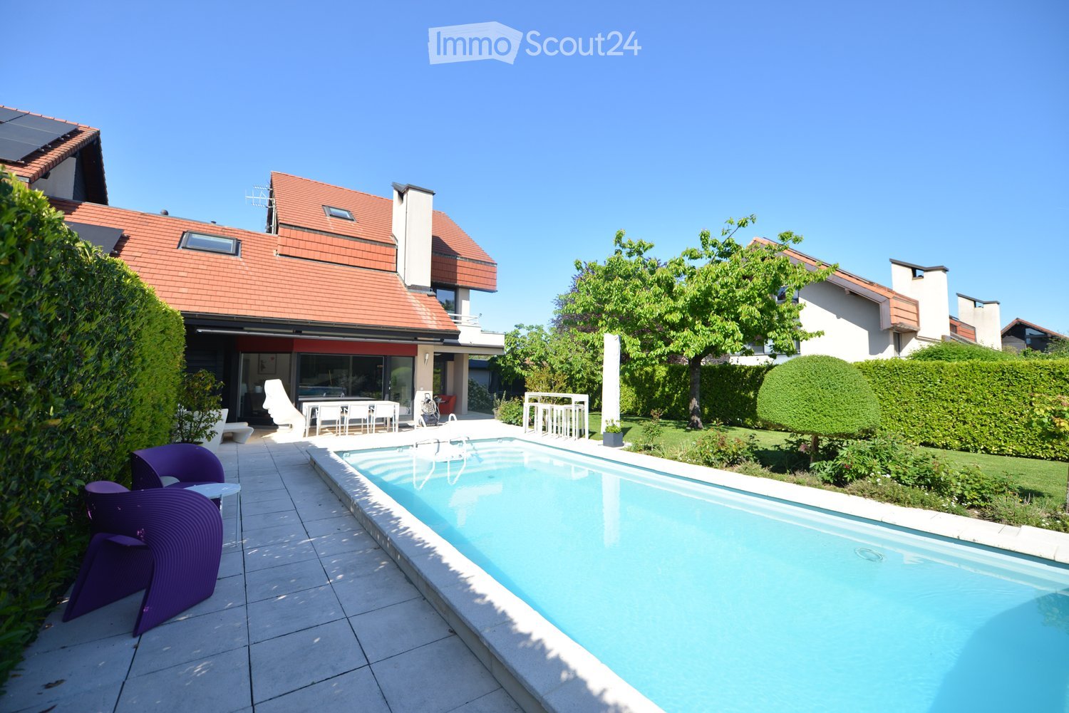 Outdoor area with a swimming pool, patio furniture, and greenery.