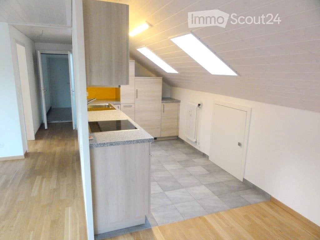 Modern kitchen with light wood cabinets, granite countertop, stainless steel sink, and stove. Skylight windows provide natural light. Wooden flooring throughout.