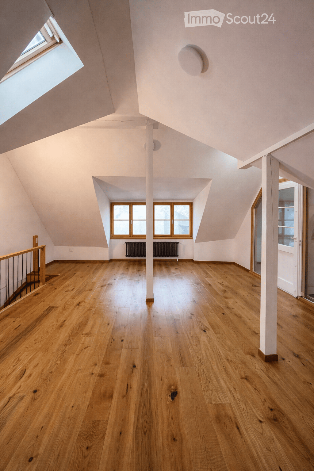 empty attic room, wooden floor, skylight, windows, wooden support column, open door