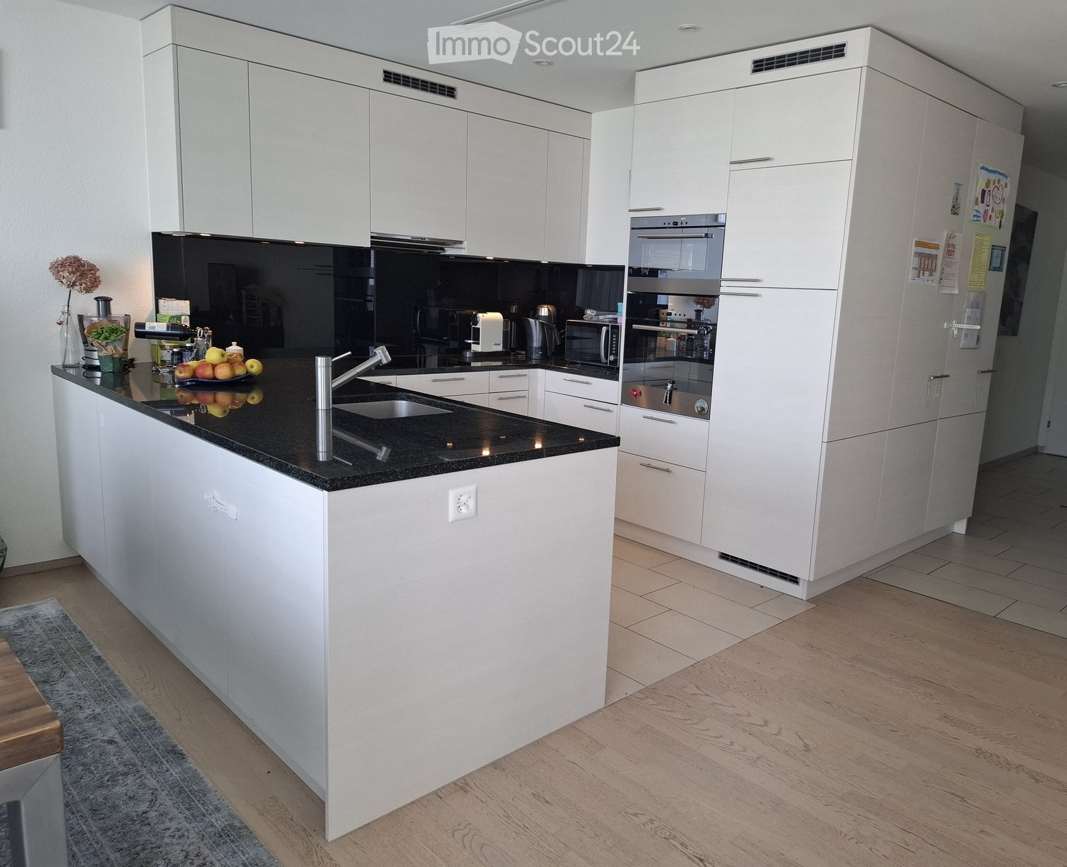 Modern kitchen with white cabinets, black countertops, stainless steel appliances, and a central island with a sink and faucet.