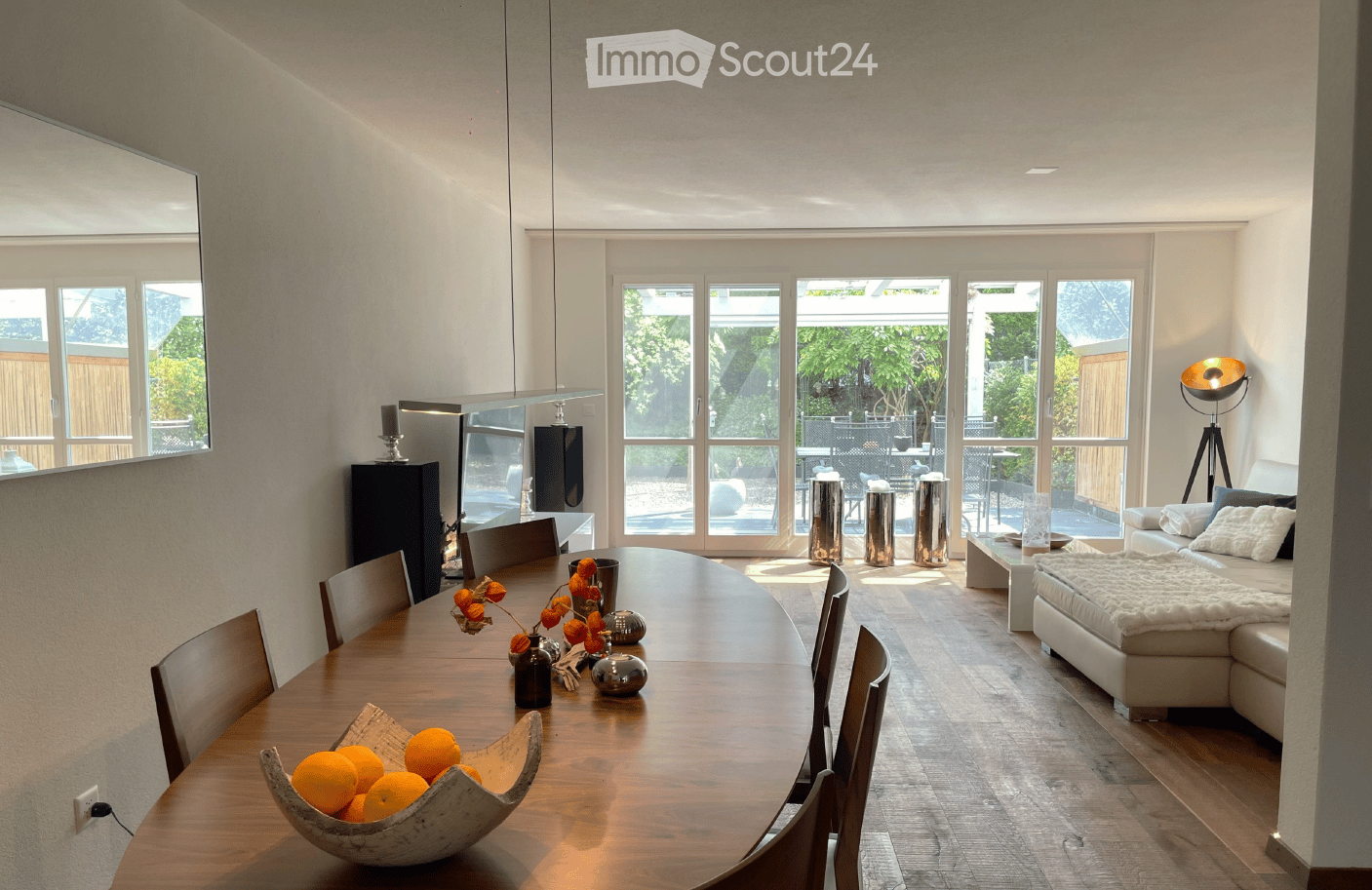 Open-plan living and dining area with large windows, modern furniture, and a view of the garden.