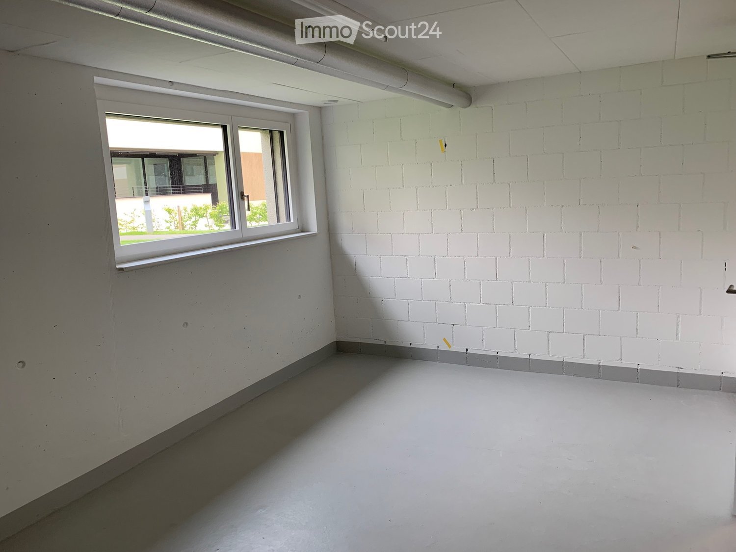Empty room with white walls, a window, and concrete floor