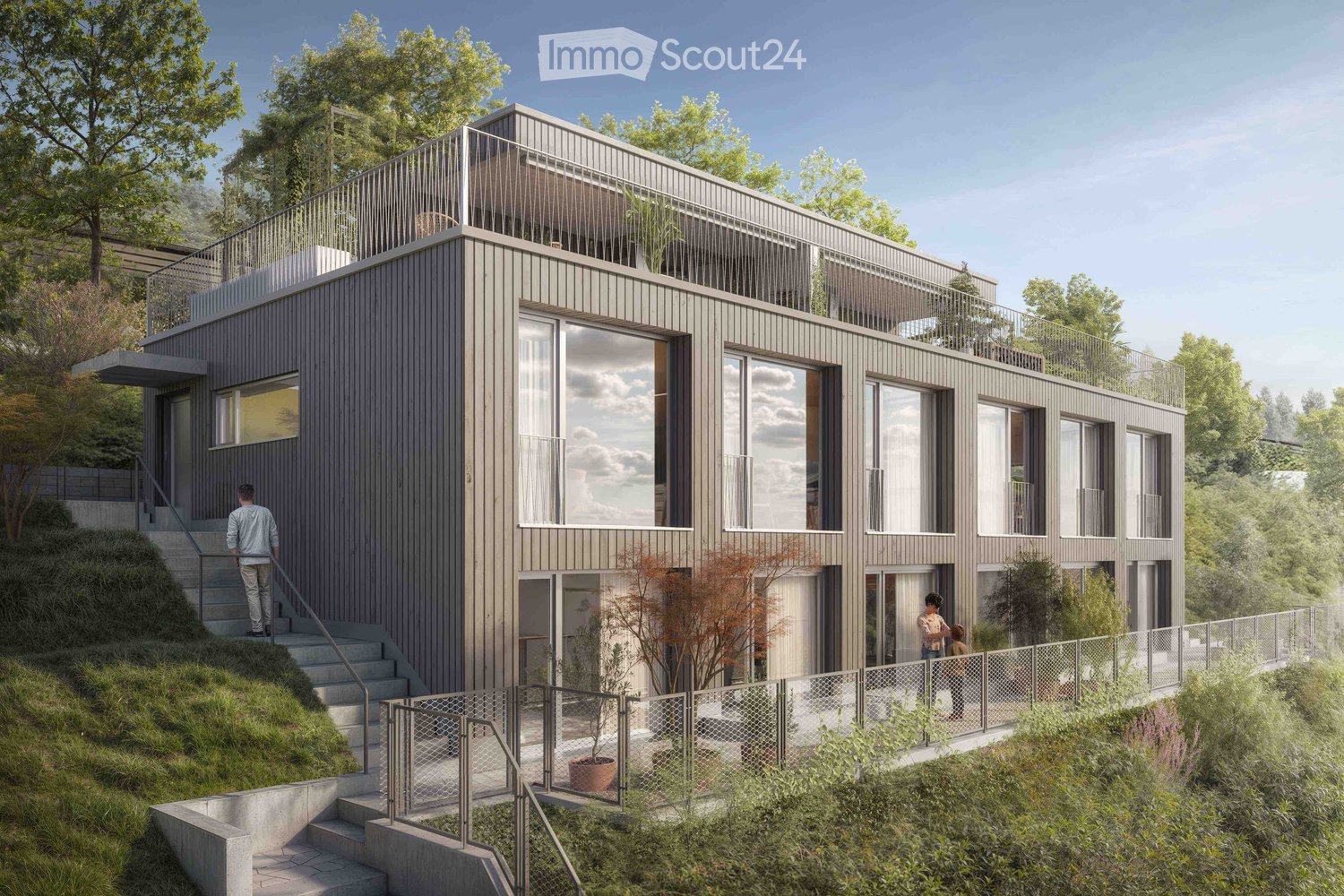 Modern two-story house with grey wooden facade, large windows, and balconies, situated on a raised ground floor with surrounding greenery and trees.